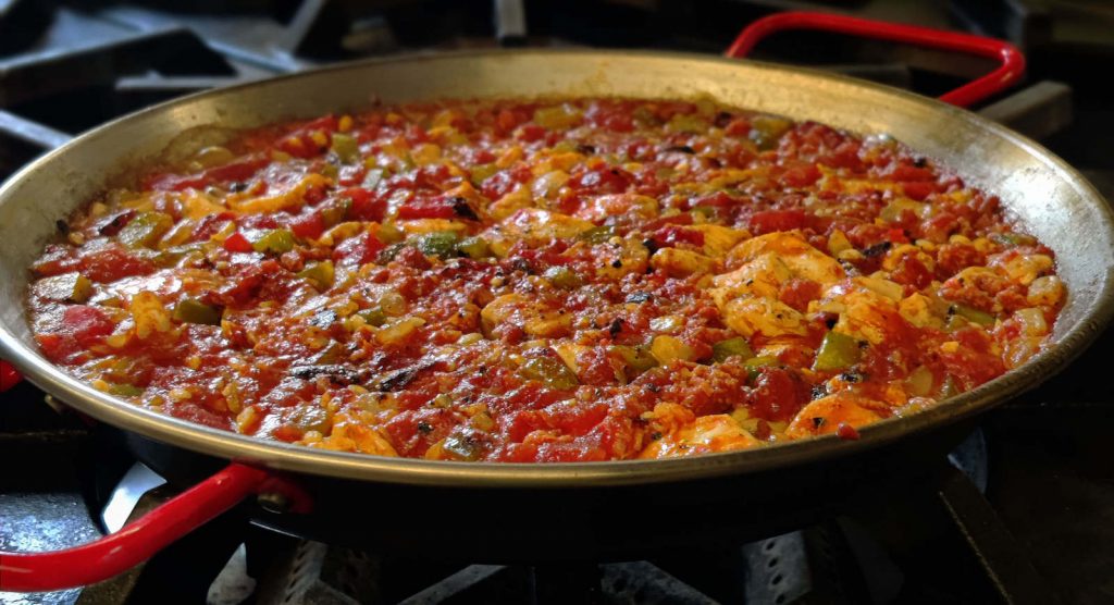 A delicious Spanish paella being cooked in a large pan during a private cooking group class with Tania Lopez in New York.